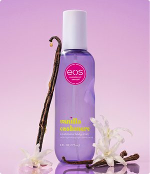 EOS Vanilla Cashmere body mist bottle with vanilla bean and flowers on a purple background
