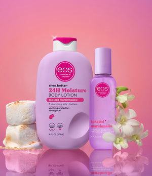 Two eos bottles, a larger lotion bottle and a smaller spray bottle, on a pink background with marshmallows and flowers.