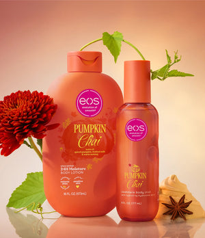 Two EOS Pumpkin Chai moisturizing body care products, a large pump bottle and a smaller spray bottle, styled with a red flower, green leaves, and star anise against a warm peach gradient background.