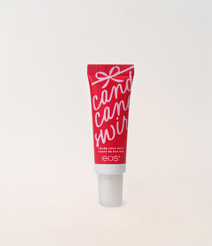 A red squeeze tube of EOS Cosmetics 'Candy Cane Wreath' holiday color corrector, featuring white script lettering and a white cap, set against a clean off-white background.