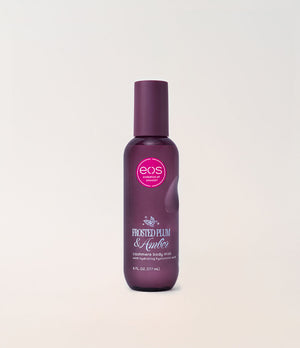 A bottle of EOS 'Frosted Plum & Amber' cashmere body mist, featuring a dark plum purple bottle and cap with a pink circular logo, set against a clean off-white background.