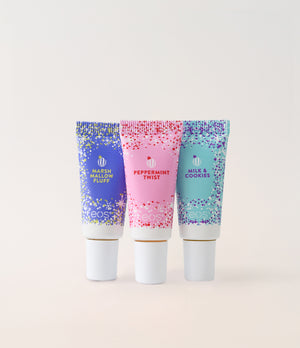 Three tubes of lip balm with colorful packaging on a light pink background