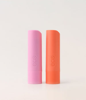 Two EOS lip balm tubes, one pink and one orange, on a light gray background.