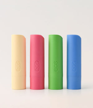Four cylindrical EOS lip balm containers in different colors on a light gray background