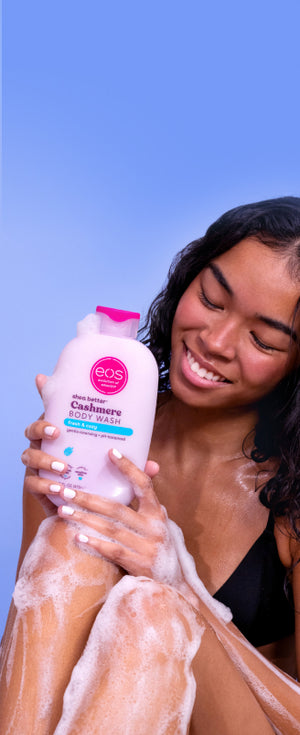 Woman applying lotion to her arm with a blue background